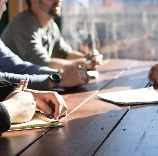 Profissionais em uma reunião, discutindo ideias e fazendo anotações